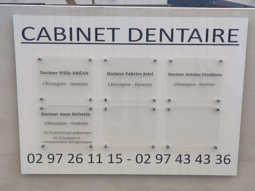 Panneau d'affichage d'un cabinet dentaire avec contacts et noms des praticiens.